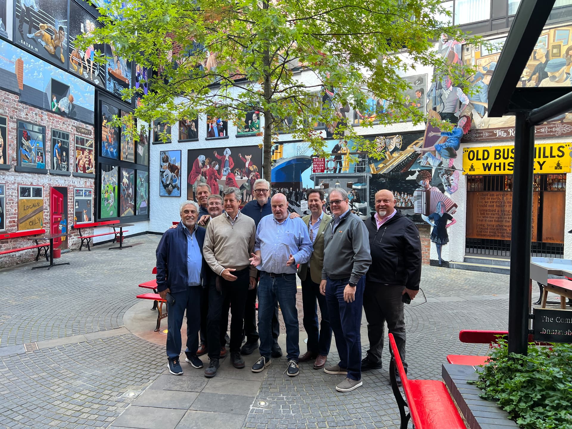 A group of men gathered together in a mural-lined courtyard in Belfast