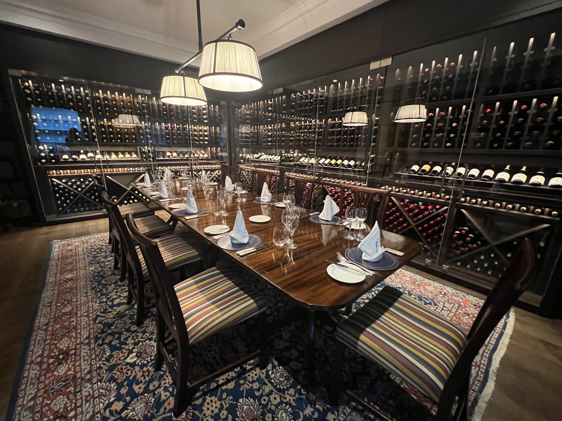 A quiet dining room set for a private gathering, wine cellar in the background
