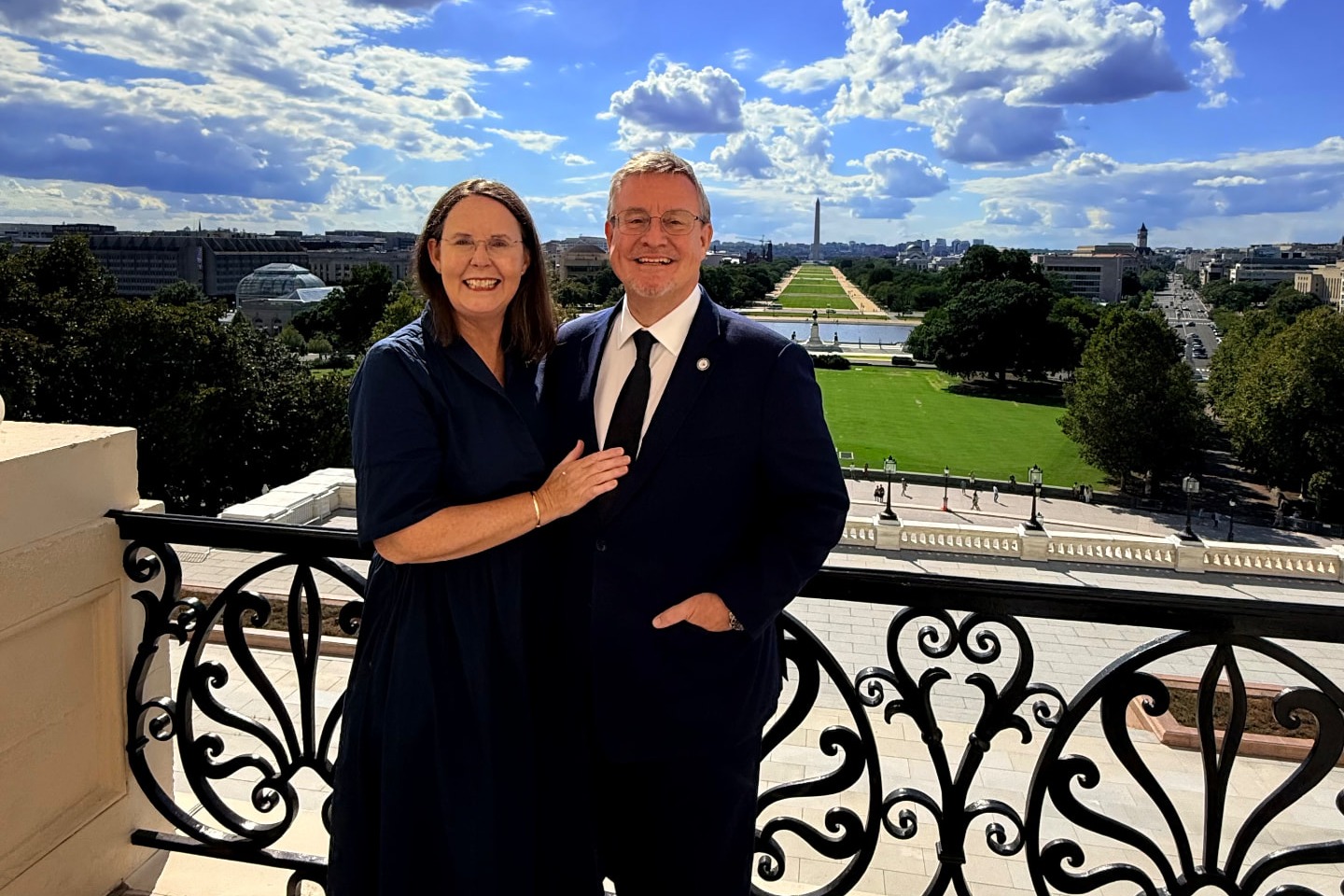 Mark and Karen Finlay on the Speaker's Balcony at the U.S. Capitol, with the National Mall and Washington Monument behind them