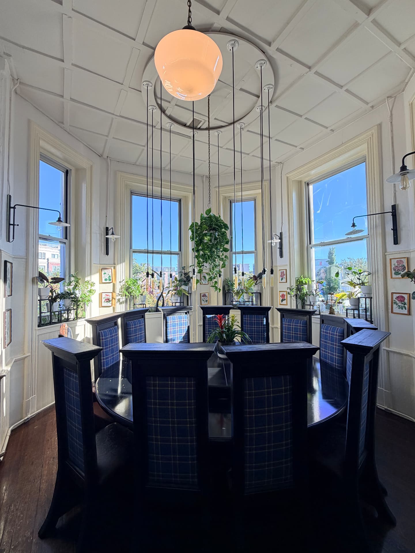 A round table with high-backed plaid chairs in a light-filled room