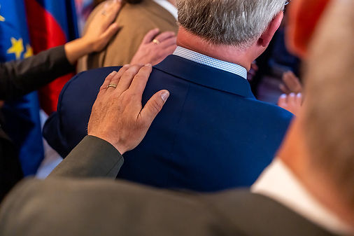 A hand resting on a shoulder in prayer
