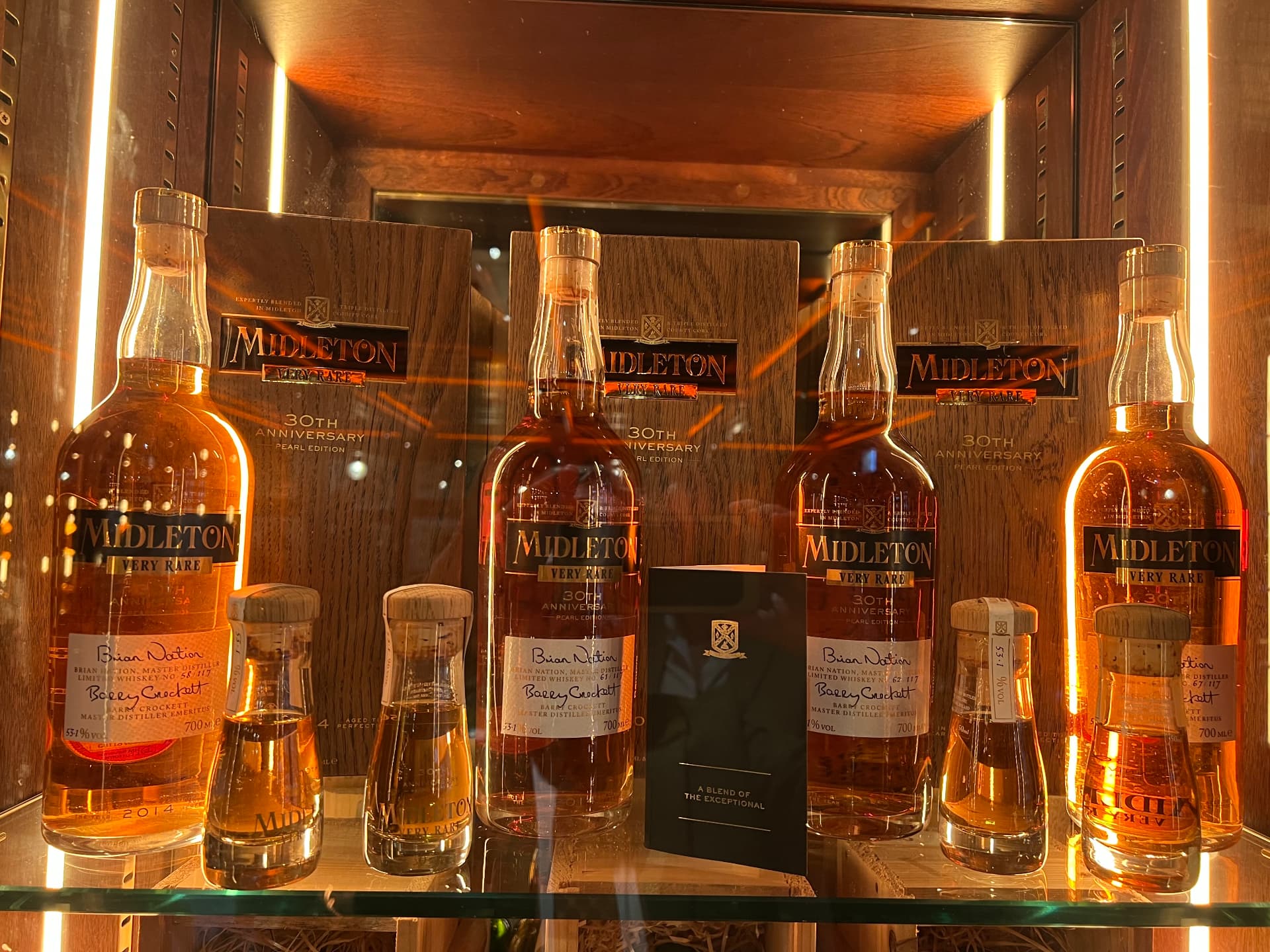 Signed bottles of Midleton Very Rare in a lit cabinet